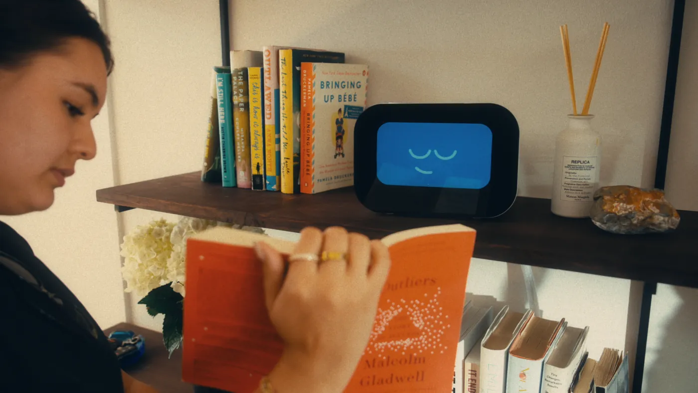 Woman reading a book beside a shelf where Rhem rests with a calm face