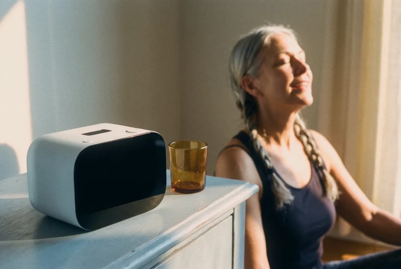 Rhem on a dresser in the morning sun while a woman relaxes in the background