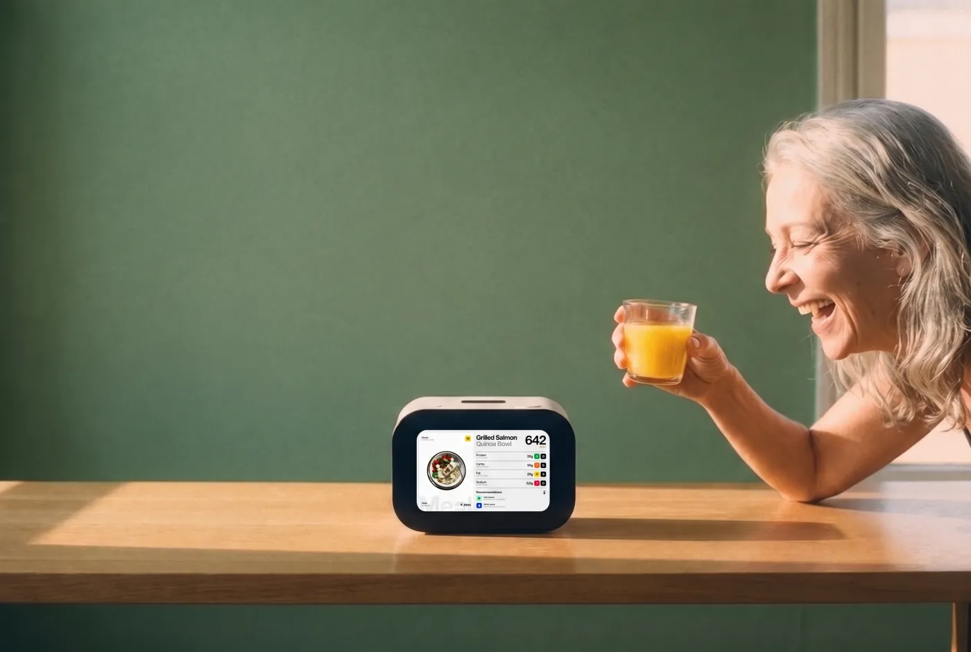 Older woman laughing over a glass of orange juice with Rhem on the table in front of her