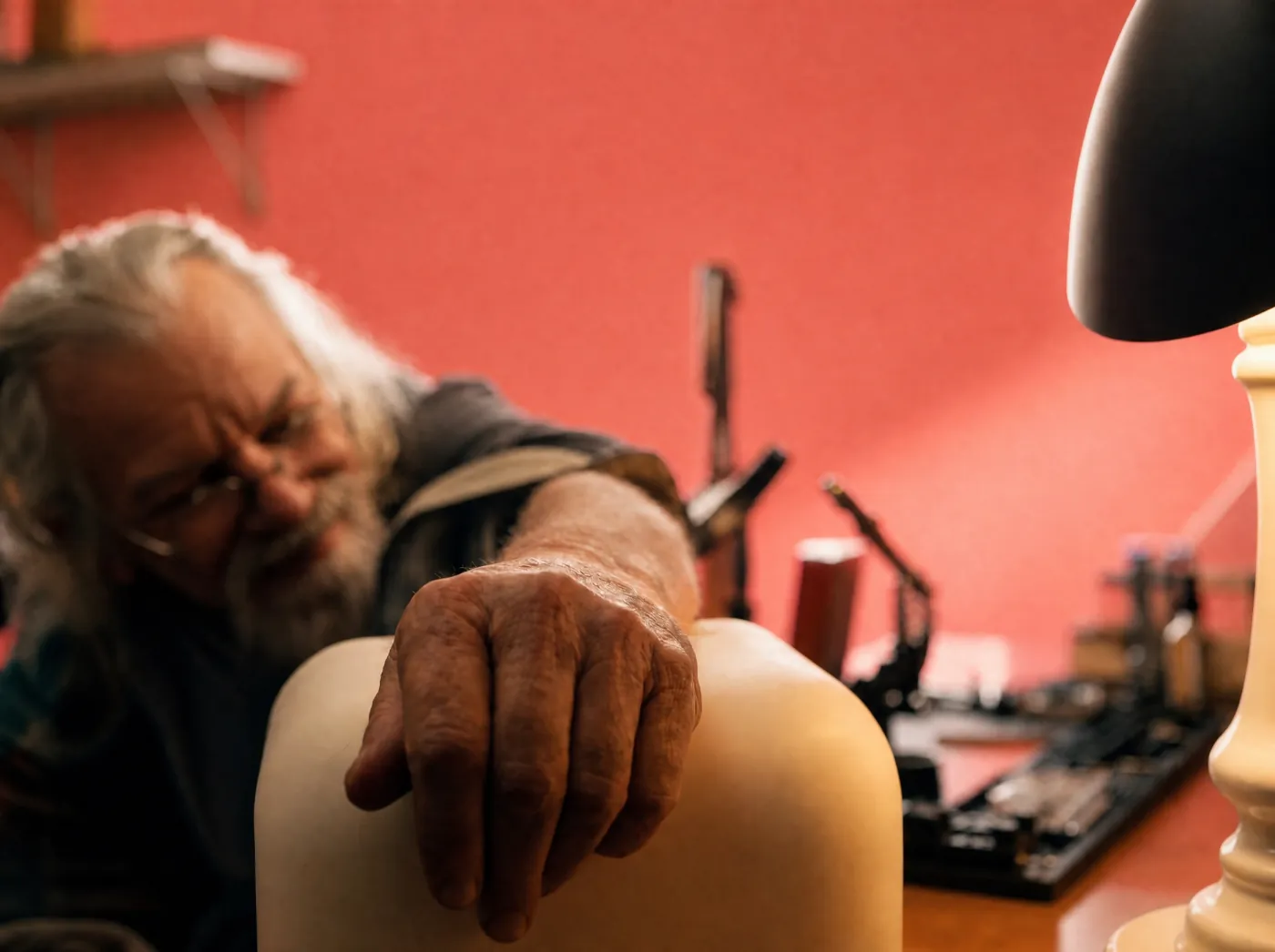An older man resting his hand on Rhem in his workshop
